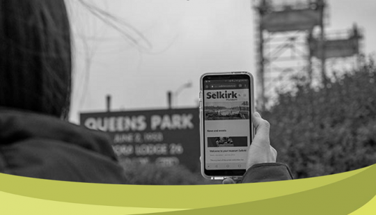 This is a photo of someone holding up their phone, with the Selkirk website on their screen.