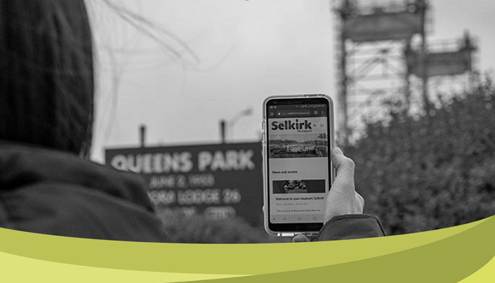 This is a photo of someone holding up their phone, with the Selkirk website on their screen.