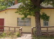 A banner of a yellow house with red doors and tree in front of it, with blue banner stripes on the sides.