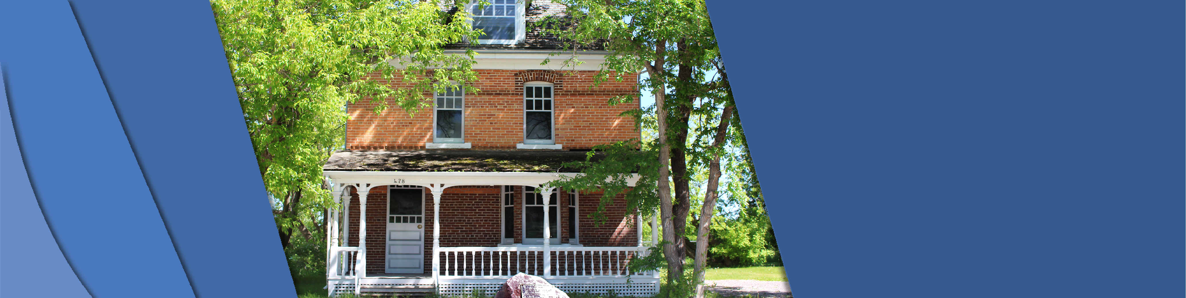 478 stuart house Picture of the front of Stuart House. You can see the porch with surrounded by a railing, the second story window and the trees on the side of the house on a summer day.