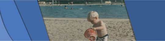 Photo of Child playing at rotary lake Photo shows a young child playing in the sand with a bucket at the poolside