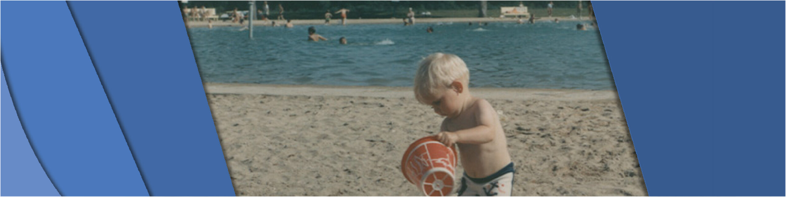 Photo shows a young child playing in the sand with a bucket at the poolside