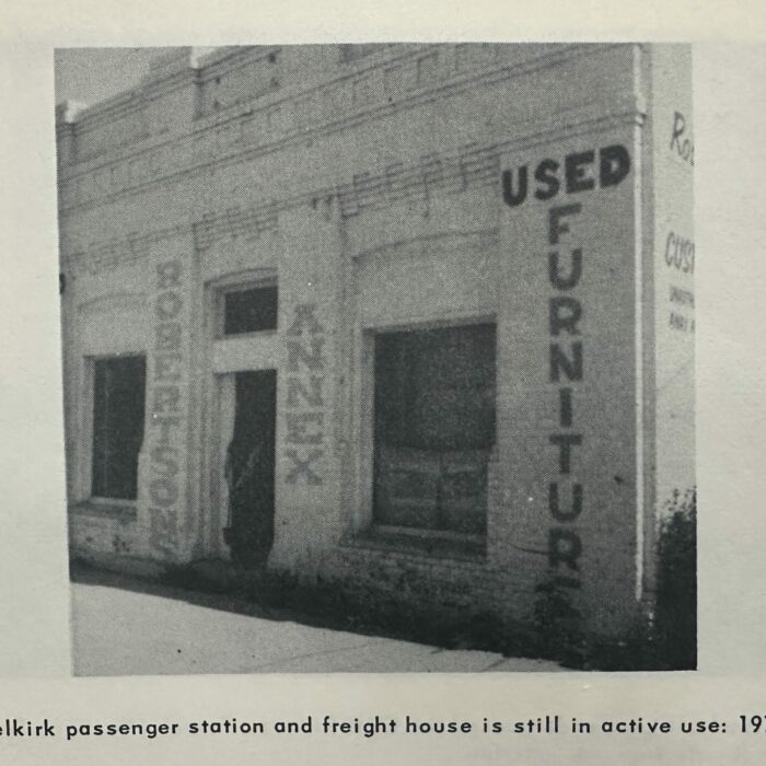 Small brick building with a door centered between two large windows. On the walls it reads 'Used Furniture' and 'Robertson Annex'