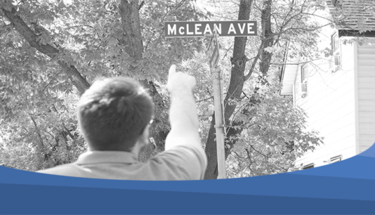 The photo shows an image of a person pointing at the street sign of McLean Avenue