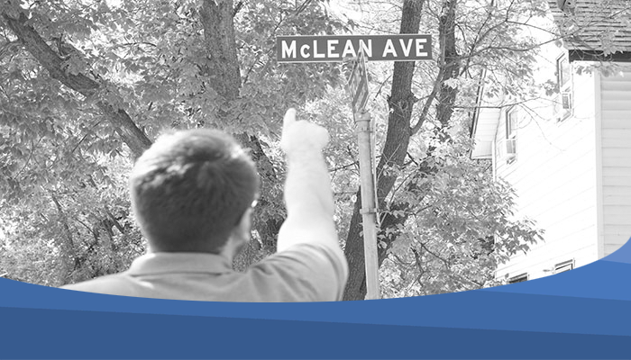 The photo shows an image of a person pointing at the street sign of McLean Avenue