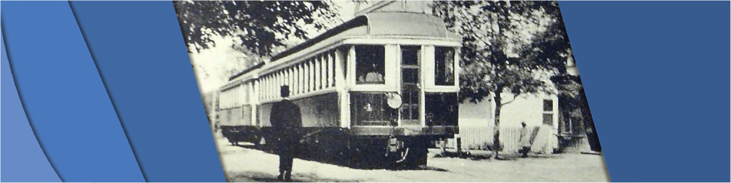 Photo of a streetcar traveling down a street with a gentleman watching it pass by.