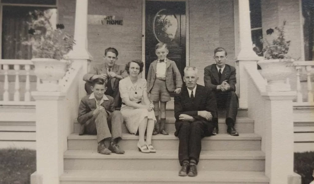Black and white photo of a family sitting on their front steps