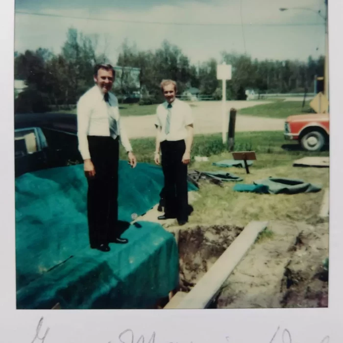 Roy and Wes in Grand Marais, June 1979, Wes Gilbart Two people wearing white shirts and ties, standing near a hole