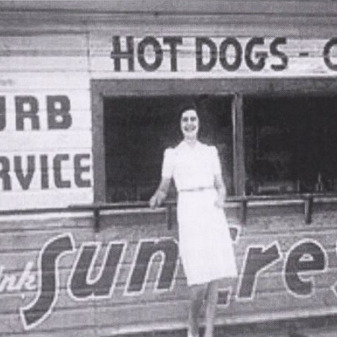 Black and white portrait of a young woman in front of a curb service restaurant