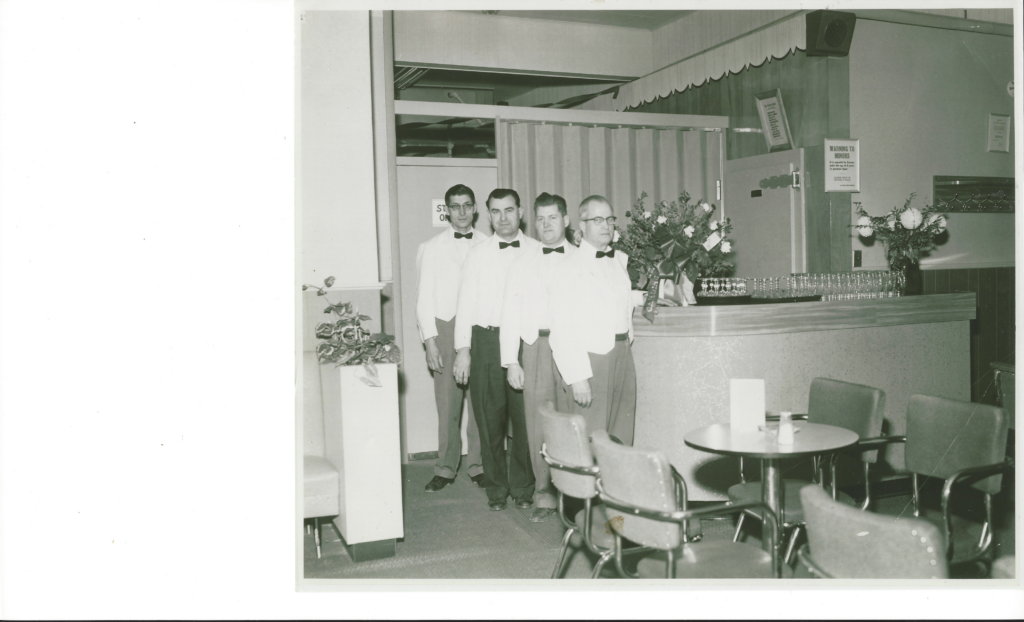 Four men standing in a foyer of a hotel wearing white tuxedos