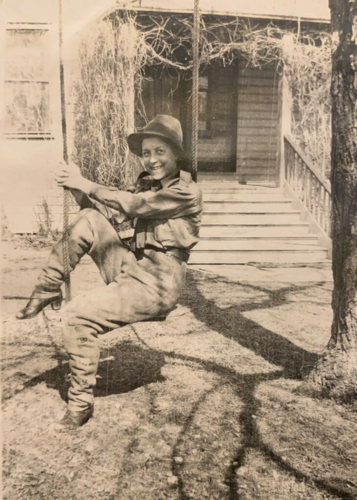 A young Ruth Moody on a swing hanging from a tree outside the Moody house
