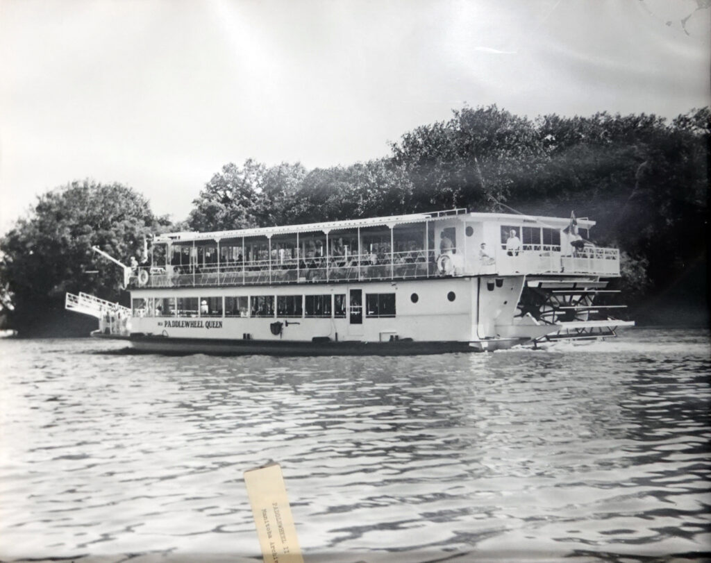 Black and white image of Paddlewheel Queen in water.