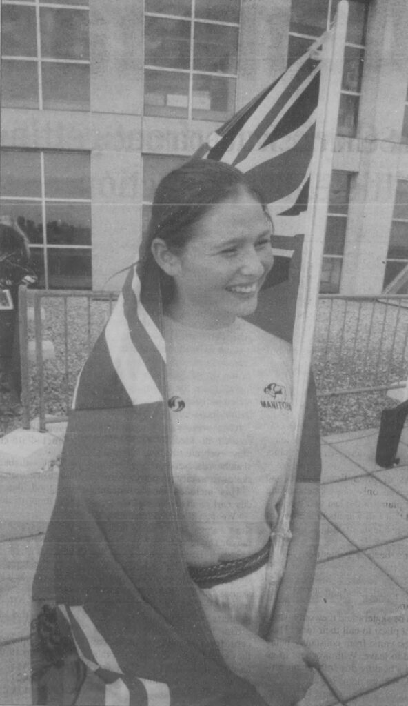 Girl smiling with the Manitoba flog wrapped around her