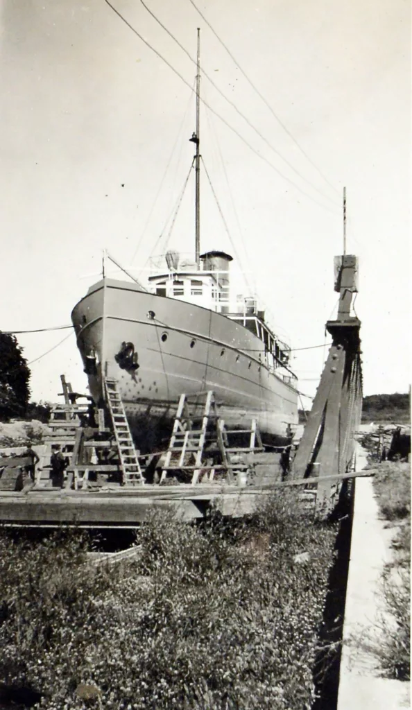 Black and white image of a boat in a dry dock having repairs.