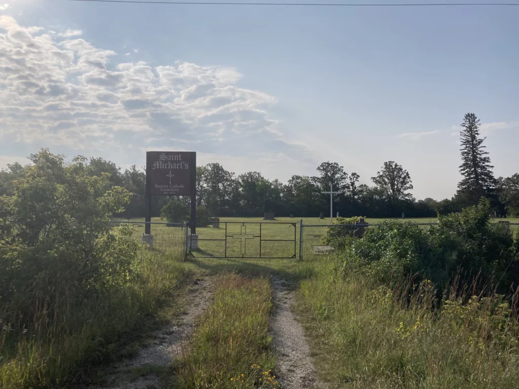 Photo of a field and sign for the cemetary.
