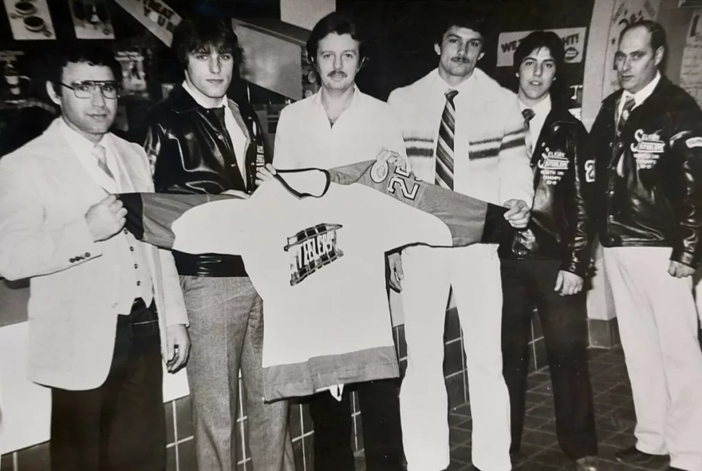 Black and white photo of a group of men holding a hockey jersey.