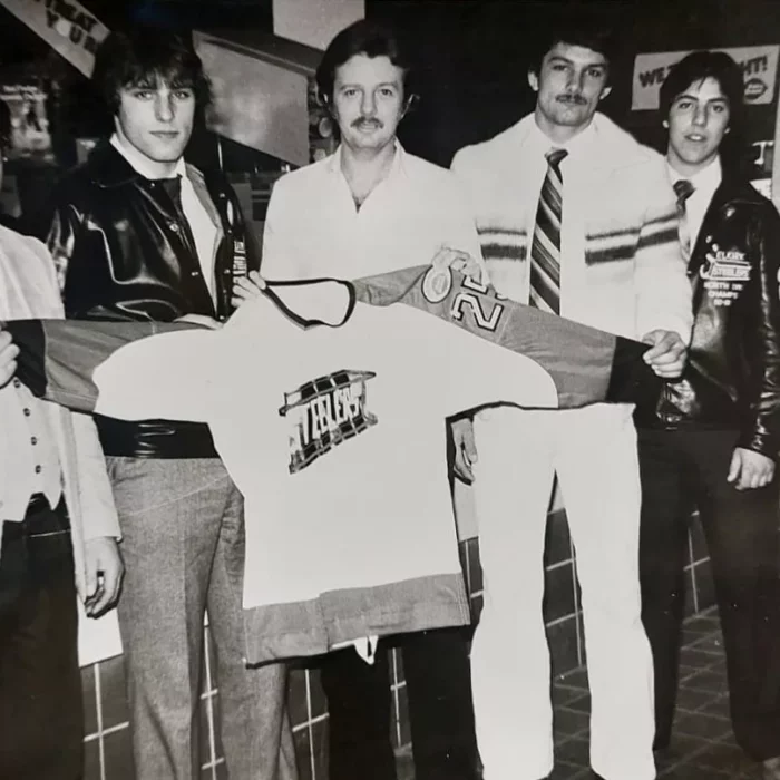 Black and white photo of a group of men holding a hockey jersey.