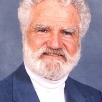 Dr. Ian L Reid wearing a white turtleneck and blue coat
