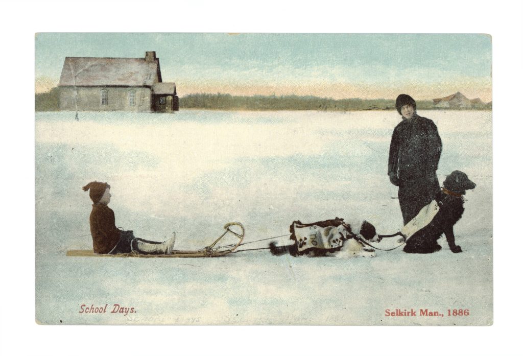 Child sitting on a dog sled with a man looking toward the camera