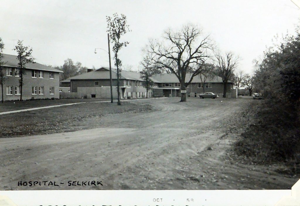 The Selkirk General Hospital shown in black and white with a dirt parking lot
