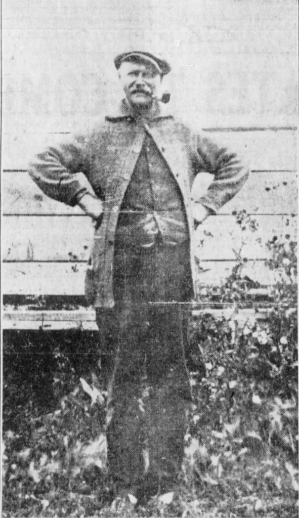 Photo of a man with a pipe in his mouth.