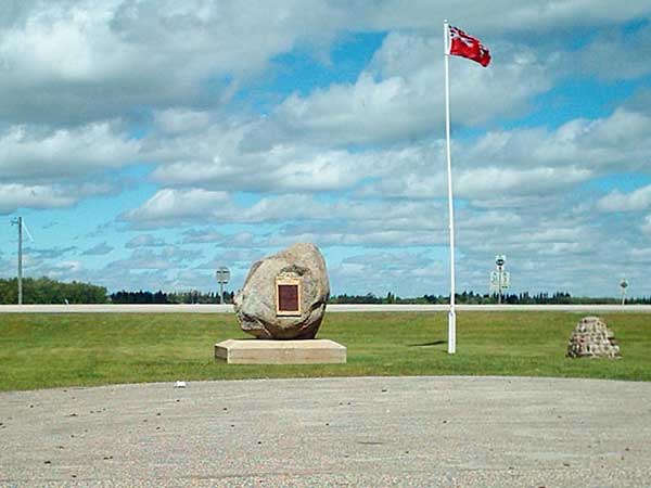 Monument stone at center of image with a Manitoba flag pole to the right