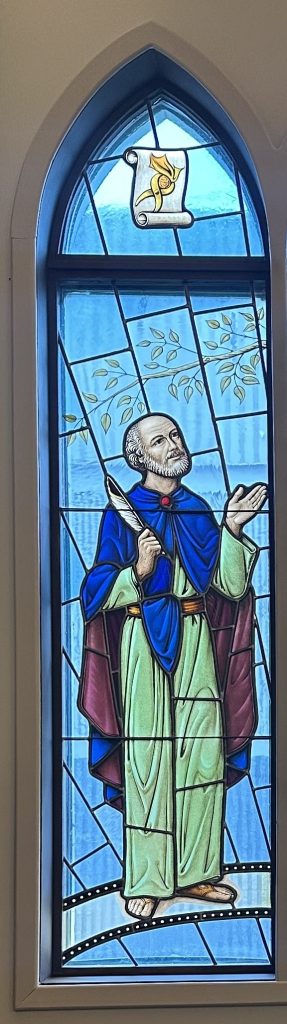 Isaiah wears a green and blue robe and holds a quill pen
