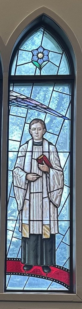 Archdeacon Jacob Anderson wears white robes and holds a red Bible