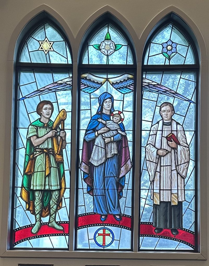 Three panel window with three figures, one in each panel. Above the figures are symbols and an arching angel's wing