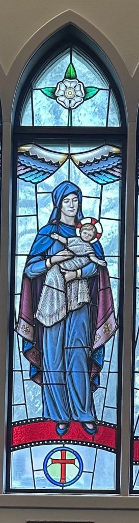 Mary holds the baby Jesus. She is wearing a blue and purple robe