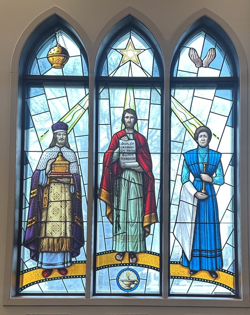 Three panel window with three people in each section. The top of each section arches and contains a motif relating to each person