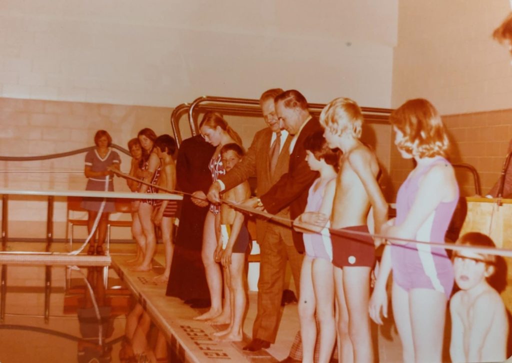 Selkirk Community Pool Ribbon Cutting. Children stand around the edge of the pool with the ribbon ready to cut it