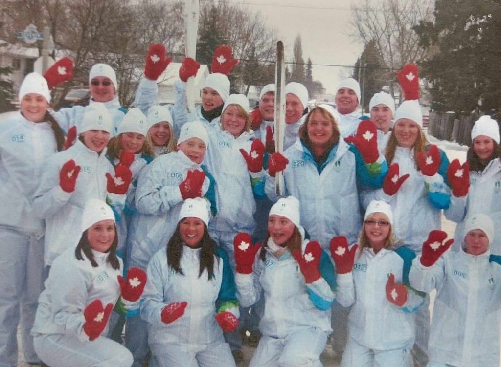 Selkirk Community Pool and Selkirk Dolphins Run the Olympic Torch posing as a group with the torch held in the center of them