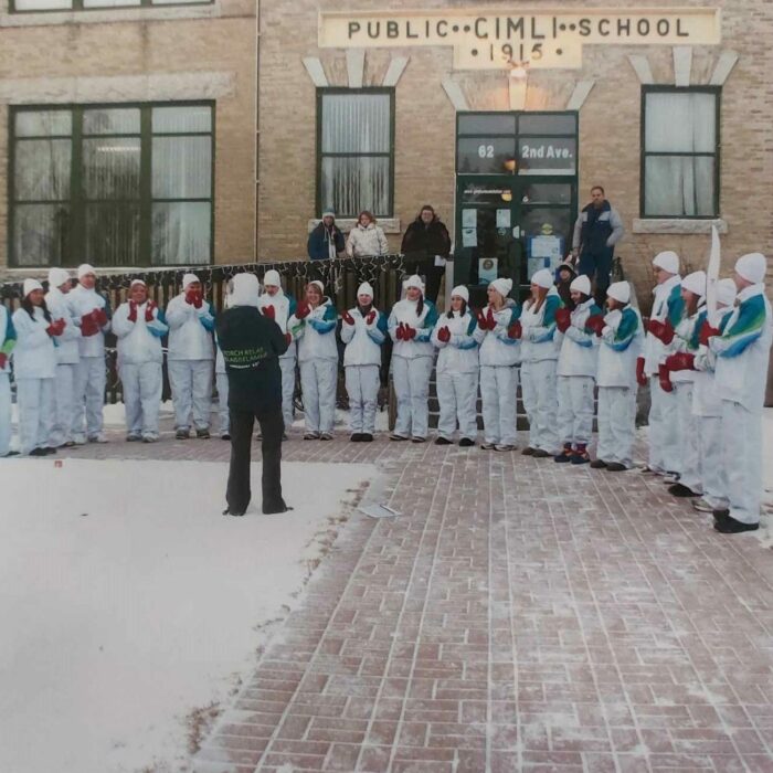 Selkirk Community Pool and Selkirk Dolphins in Gimli for the Olympic Torch Relay, 2010, Michelle Stamm Selkirk Community Pool and Selkirk Dolphins in Gimli for the Olympic Torch Relay standing in front of a brick building posing for a photo