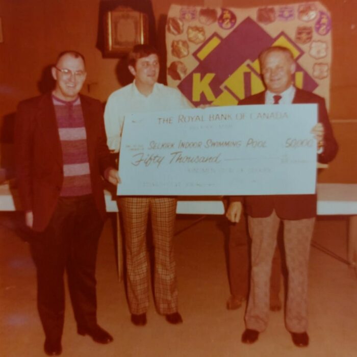 Selkirk Indoor Swimming Pool Cheque, 1974, Kinsmen Scrapbook Selkirk Museum Collection Selkirk Indoor Swimming Pool Cheque. Three people stand holding a giant sign representing the value of the donation