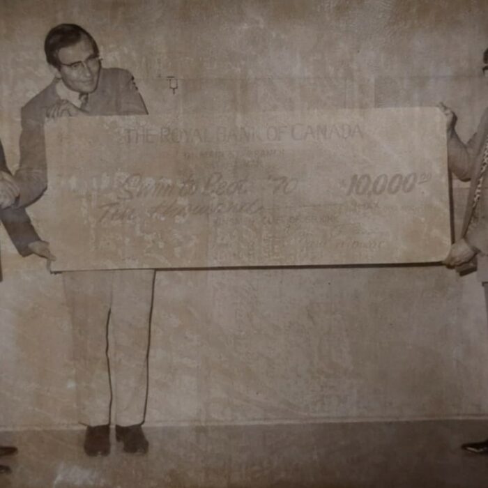 Stan Pundy, Bill Rozecki, and Gary Mowat Hold Cheque from Kinsmen for $10,000 Donation to Swim to Beat '70, 1974, Kinsmen Scrapbook Selkirk Museum Collection Stan Pundy, Bill Rozecki, and Gary Mowat Hold Cheque from Kinsmen for $10,000 Donation to Swim to Beat '70