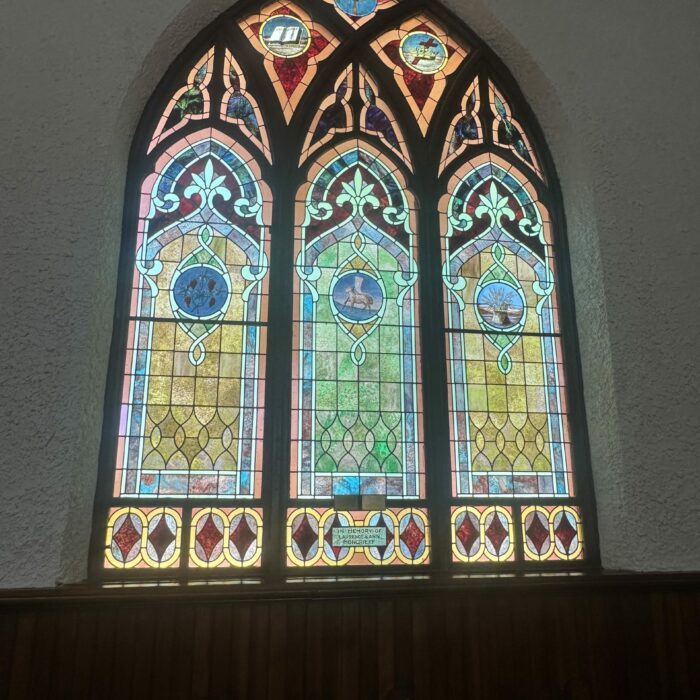 Large stained glass window with red, green, yellow, and blue. Three panels worked into one