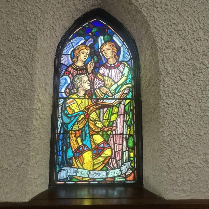Stained glass window depicting three angels holding a bible