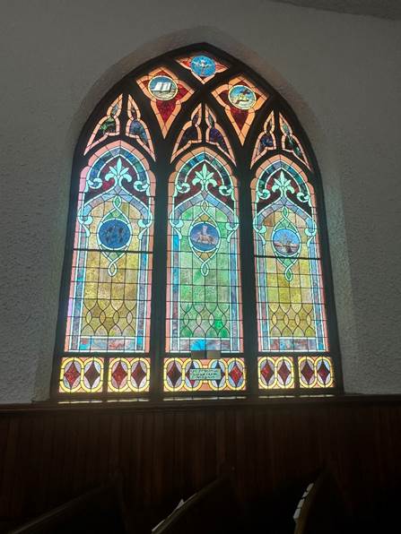 Large stained glass window with red, green, yellow, and blue. Three panels worked into one