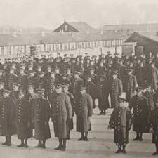 The 108th Battalion at Red Feather Farm, 1916, William Hall Black and white image of a group of soldiers standing in front of a few large barn buildings