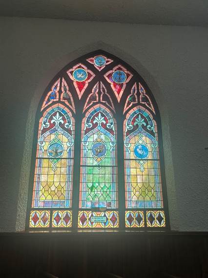 Stained glass window with red, blue, yellow, and green. Three panels worked into one