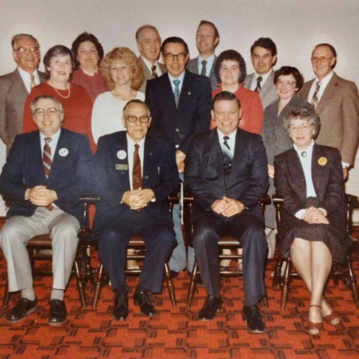 Centennial Committee Bob Wur, John Veitch, Bud Oliver, Bess Corby, Dawn MacFarlane, Florence Fedyk, Edgar Taylor, Eileen Cyr, Doreen Oliver, Hugh Williamson, Tanis Briggs, Del Reid, Dave MacLaren, Steve Banera, George Plews Colour photograph of a group of people seated and standing. They are in a room with white walls and red and black checkered floors