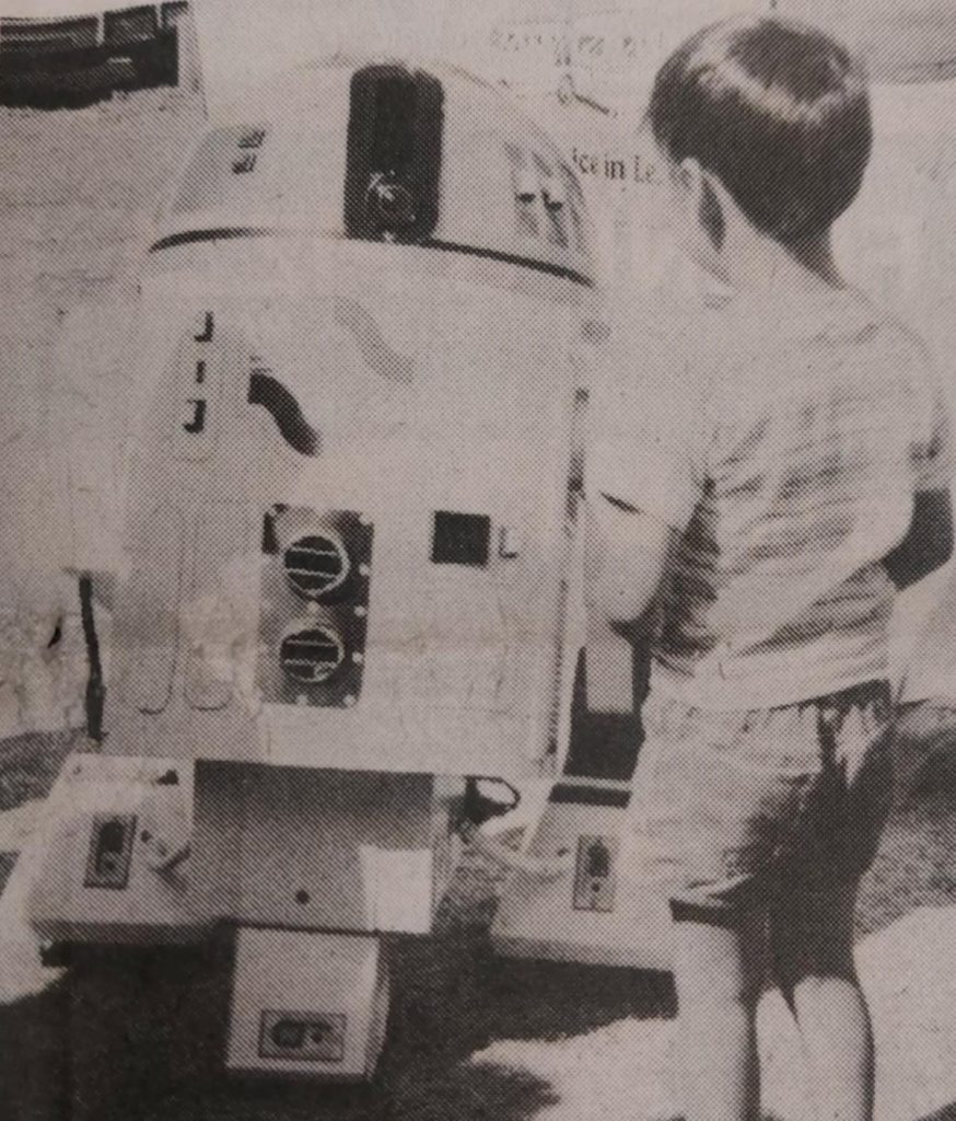 Black and white image of a young boy next to the Centennial robot