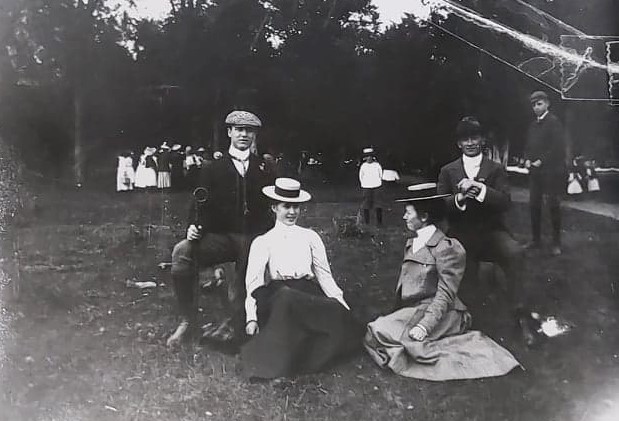 Black and white image of two young men and two young women seated on the grass at Selkirk park