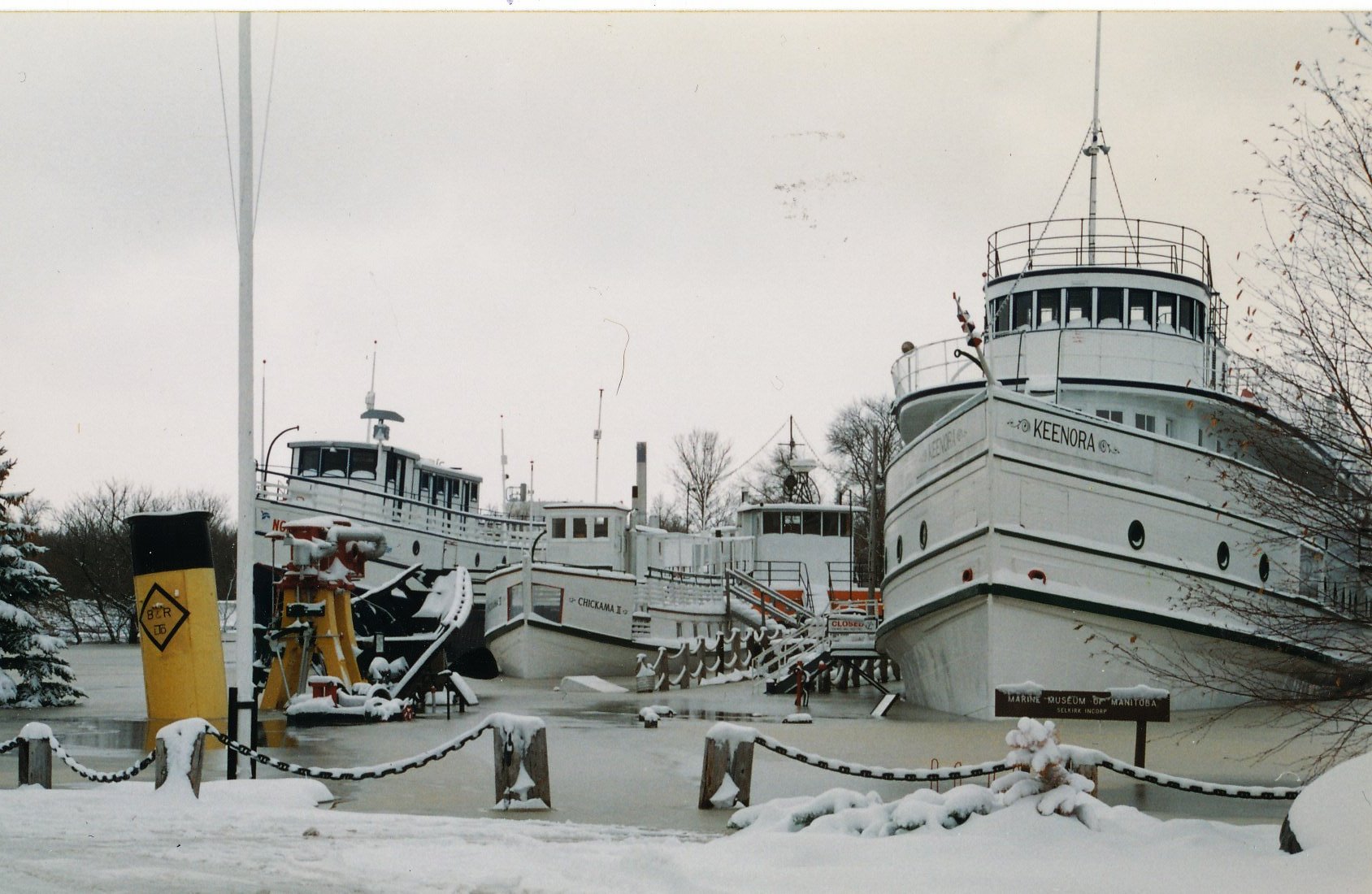 Colour photograph of the Marine Museum in the early spring right after a flood. The water has frozen around the ships