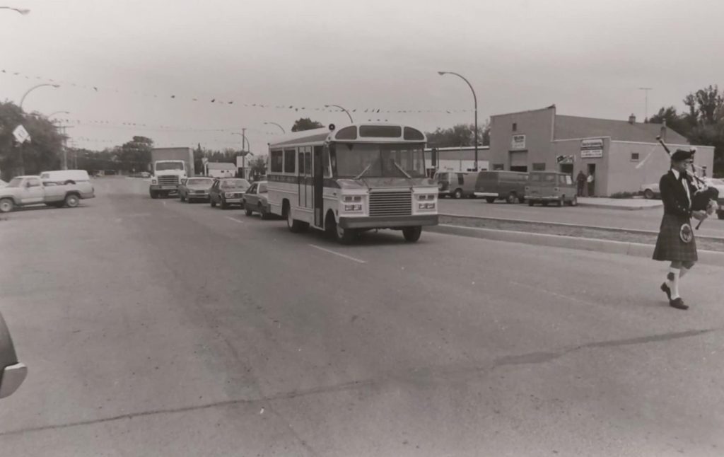 Black and white image of a bus driving down the road