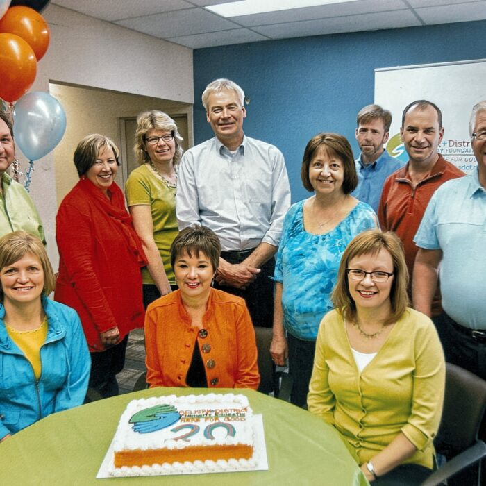 Board of Directors and Staff, Back, Doug Chorney, Shirley Muir, Heather Hogg, Stan Halbesma, Carol Wiedemann, Mark Webster, Gord Henrikson, Bill Bodman, Front, Michele Polinuk, Kelly Lewis, Bev Clegg, 2014-2015 A group of people sit and stand around a table. On the table is a cake. On the left side are orange and white balloons
