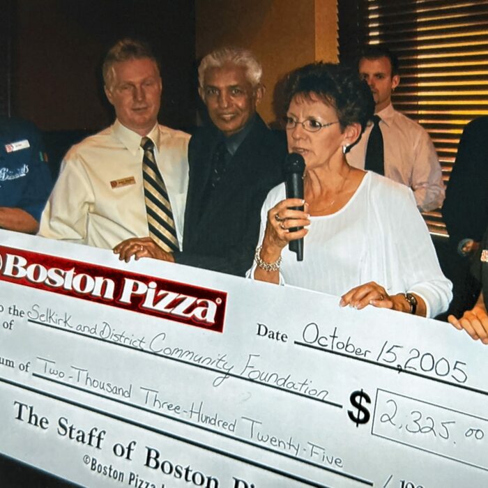 Boston Pizza's Grand Opening Gail Bodman and Ike Hussain Accept a $2325 Cheque on Behalf of the Foundation from James Allardice and His Staff, 2005, Selkirk District Community Foundation A few men and women stand holding an oversized cheque from Boston Pizza.