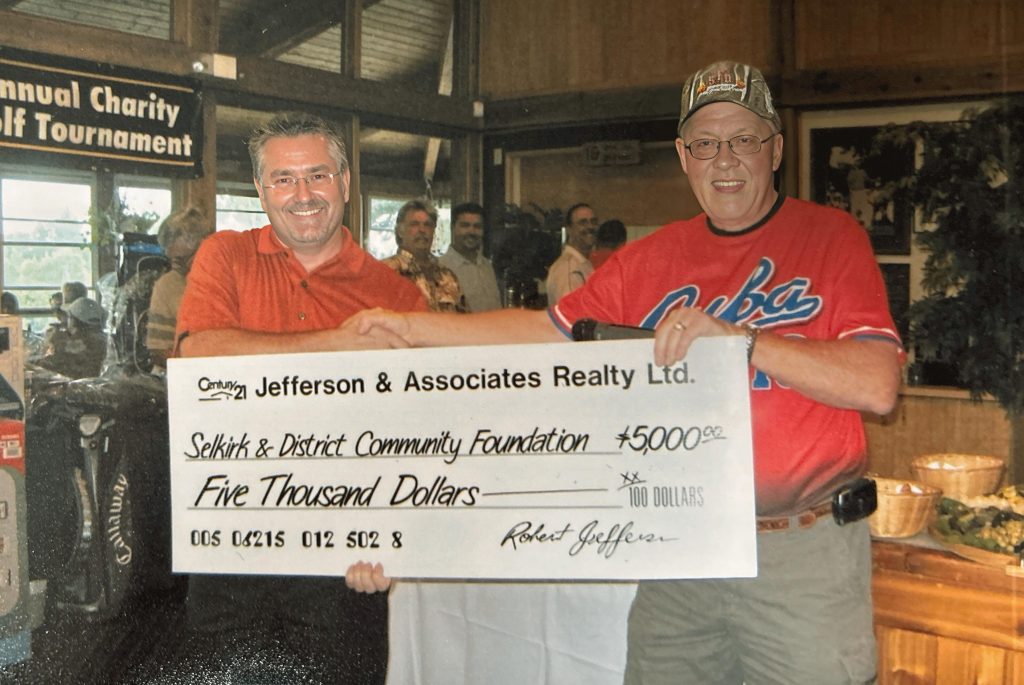 Two men stand together holding an oversized cheque
