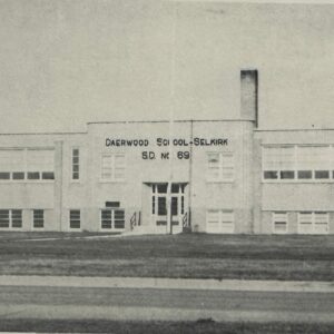 Black and white photo of Daerwood school. The sky is clear and there is grass in front of the school